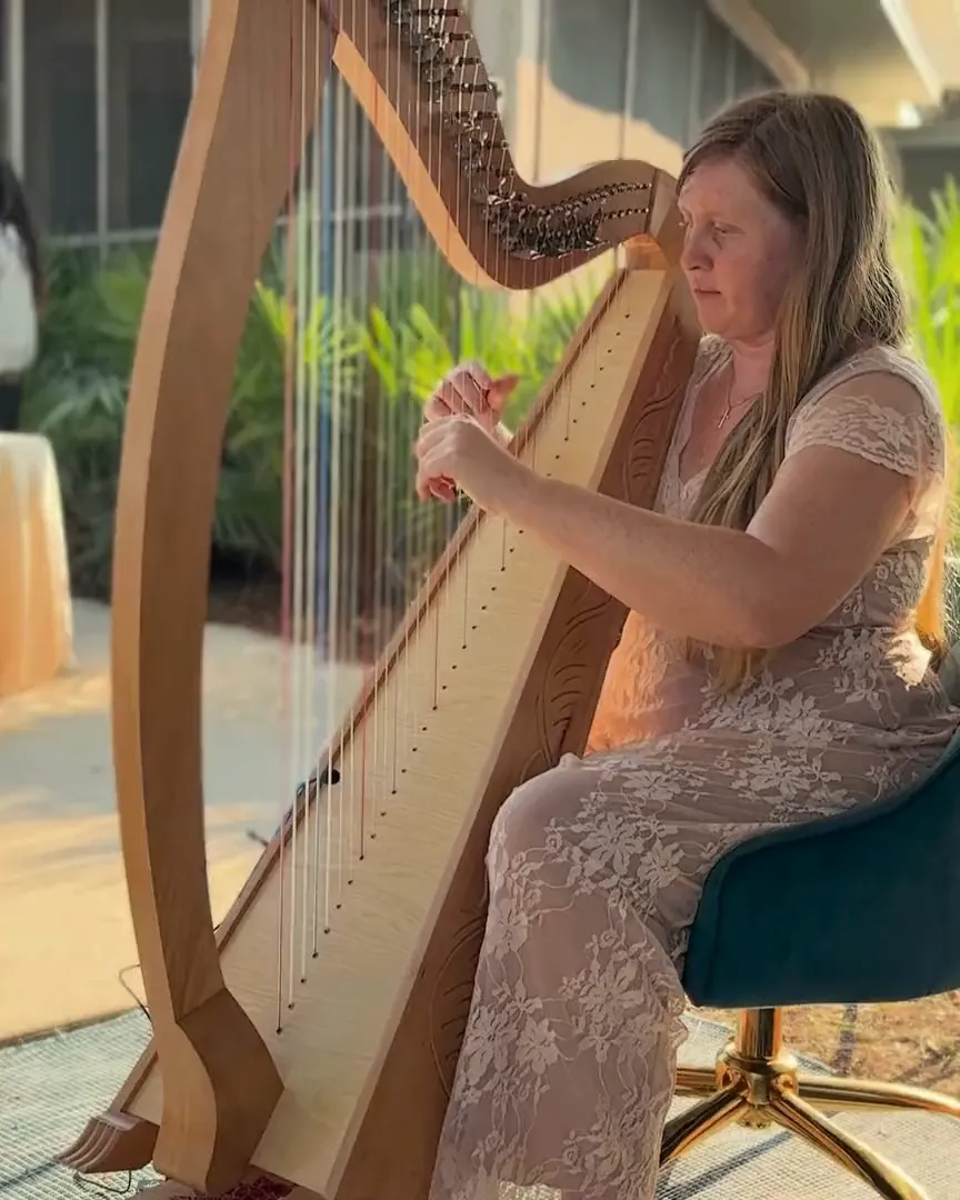 Hilary Turner playing harp at an outdoor celebration.