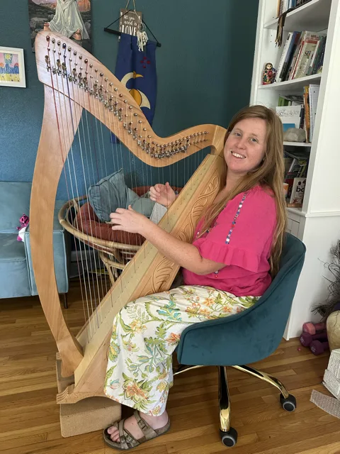 Hilary Turner smiling beside her harp.