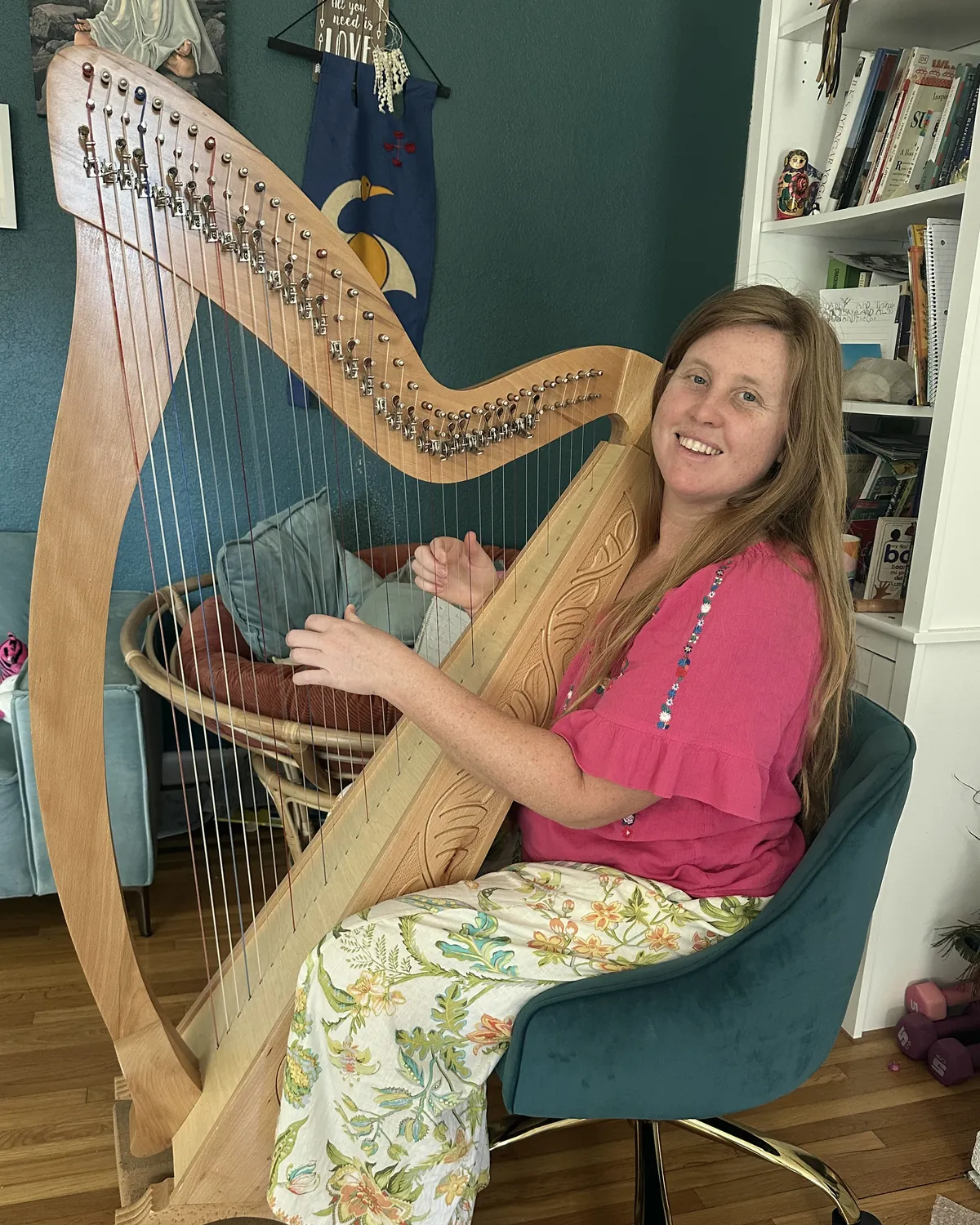 Hilary Turner smiling beside her harp at home.